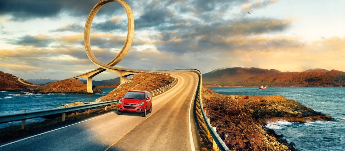 Red car driving on the road by the river