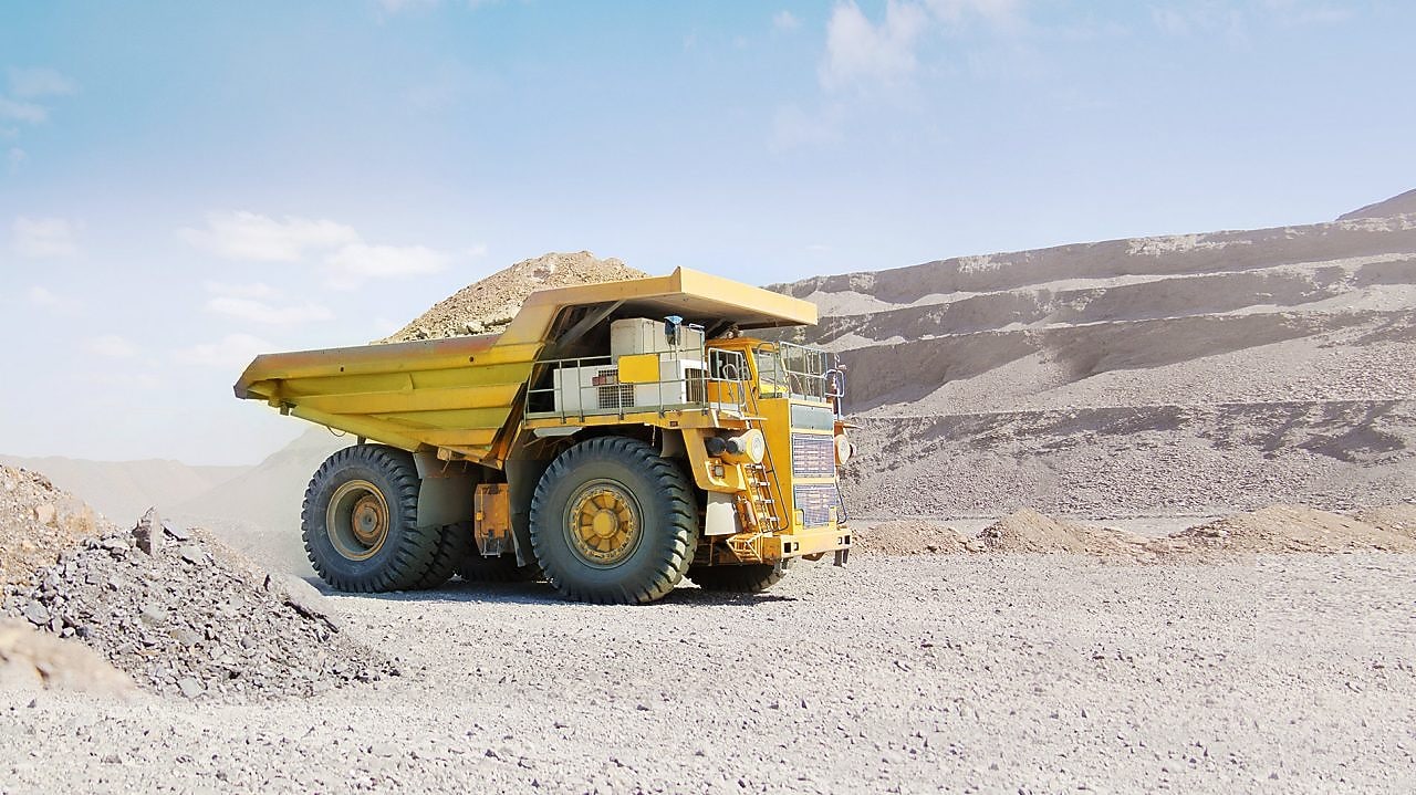 yellow dumper truck driving through gravel