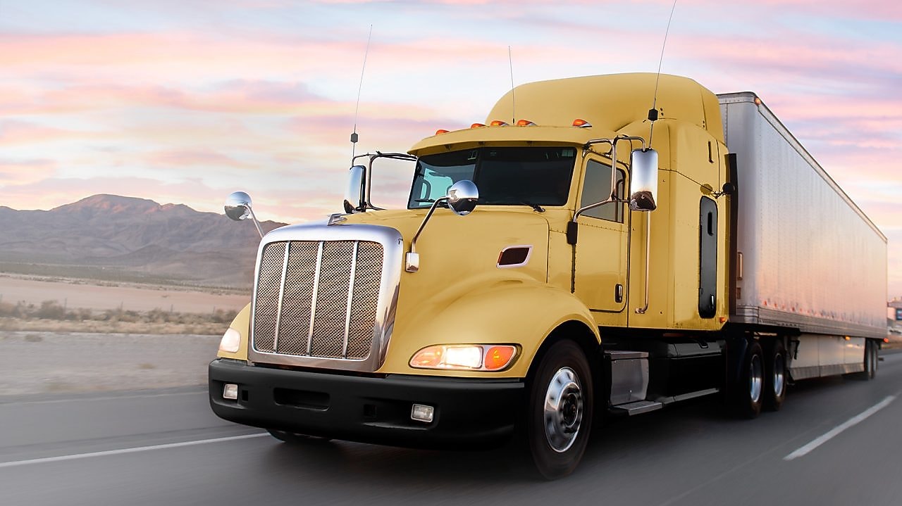 a yellow truck driving down a road at dusk