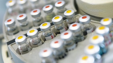 Filas de frascos de medicamentos en un soporte, algunas de ellas con puntos rojos y otras con puntos amarillos en la tapa