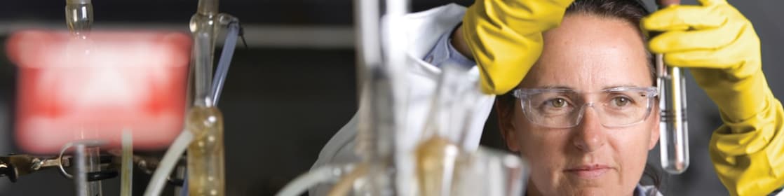 mujer con lentes de seguridad llevando a cabo un experimento de laboratorio