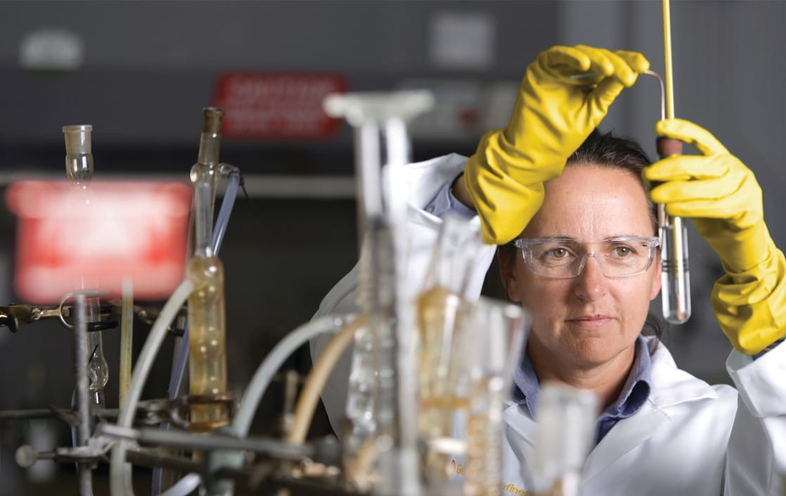 mujer con lentes de seguridad llevando a cabo un experimento de laboratorio
