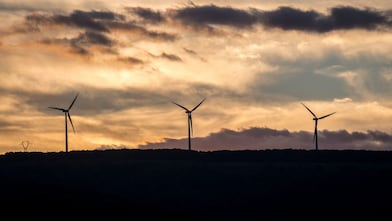 Tres centrales eólicas con el sol poniéndose al fondo