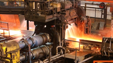 Hot steel being rolled to shape in mill in steel manufacturing plant