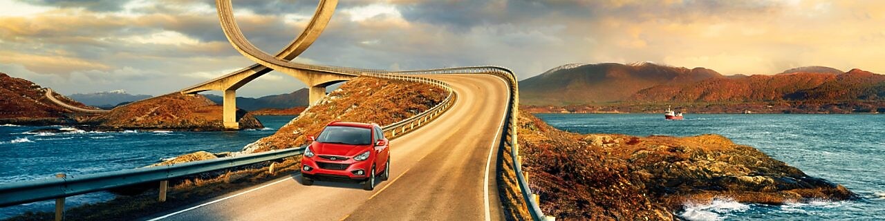 Red car driving on the road by the river