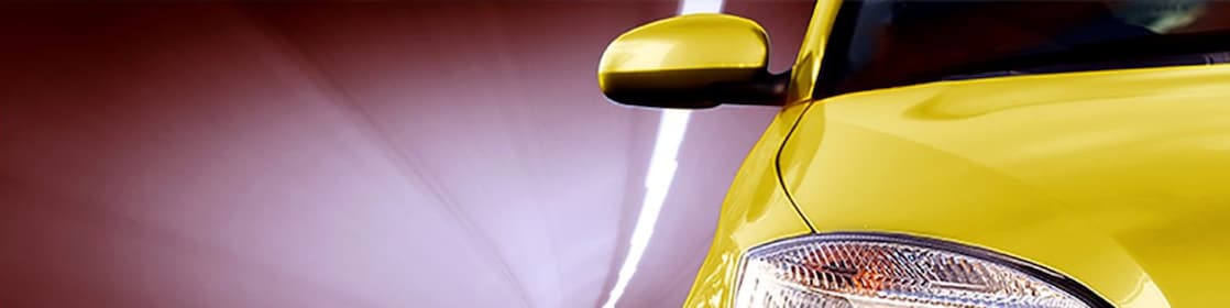 Parte frontal de un coche amarillo circulando por un túnel, con vista del faro delantero y el espejo lateral derechos