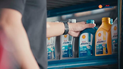 Mano tocando las botellas de Shell Advance en un estante