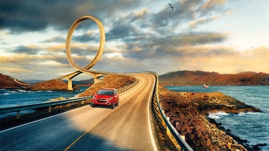 Red car driving on the road by the river