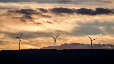 Tres centrales eólicas con el sol poniéndose al fondo