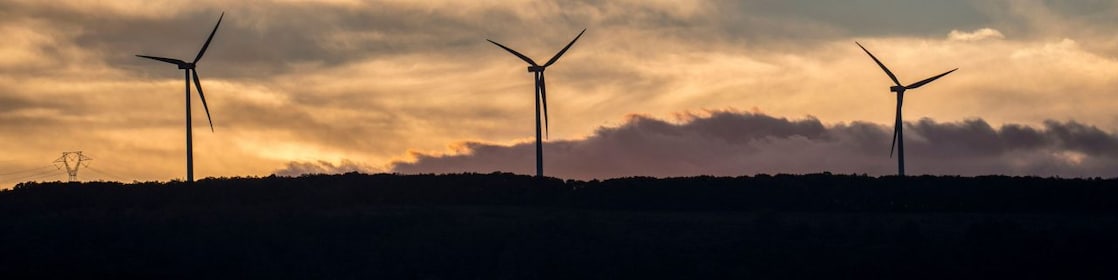 Tres centrales eólicas con el sol poniéndose al fondo