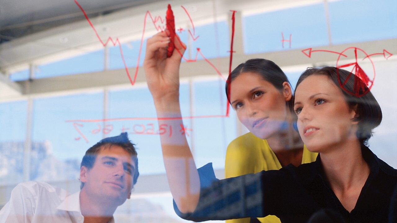 Mujer de negocios dibujando gráficos en una pizarra transparente