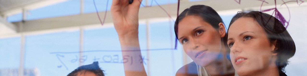 Mujer de negocios dibujando gráficos en una pizarra transparente